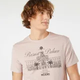 Remera color rosa claro con cuello redondo y manga corta. Estampado frontal con el dibujo del Royal Resort Palace Hotel de Miami.