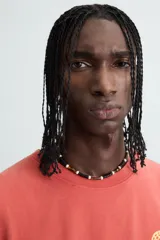 Camiseta tank cropped fit color ladrillo, con cuello redondo y sisa. Estampado frontal y trasero con gráficos y textos en color amarillo. Efecto lavado.