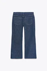 Pantalón de jean celeste de tiro bajo, corte flare, cropped y cinco bolsillos.