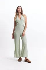 Mono largo color crudo, con escote halter, espalda descubierta y corte palazzo.