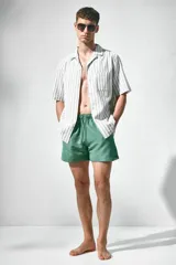 Short de baño verde con elástico y cordón ajustable en la cintura, bolsillos laterales y trasero con cierre autoadherente.
