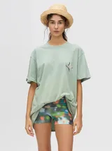 Remera verde agua de corte cuadrado y holgado, con cuello redondo y manga corta. Presenta un pequeño logo bordado en el pecho.