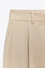 Pantalón negro de tiro alto con bolsillos delanteros, pinzas y corte ancho.