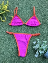 Bikini de dos piezas color fucsia con bordes en naranja. El corpiño es triangular con tirantes finos y la bombacha es colaless regulable con tiras finas laterales.