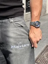 Pantalón de jean gris oscuro con corte amplio y estampado con el logo de la marca en la pierna izquierda.