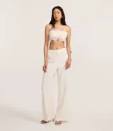 Pantalón flare de tejido plano color blanco, con trabillas en la cintura, cierre tradicional, frisos delanteros y bolsillos falsos atrás.