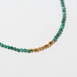Collar corto de cuentas facetadas verdes y doradas.