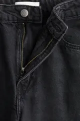 Jean de cinco bolsillos en denim de algodón, color negro lavado. Presenta un corte de tiro alto con piernas curvas de estilo baggy, con volumen en cintura y cadera, y ligeramente más ajustado desde el muslo hacia abajo.