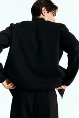 Campera bomber deportiva negra, confeccionada en tejido funcional DryMove™ que absorbe el sudor. Presenta cuello elevado corto, cierre bidireccional, mangas raglán y bolsillos delanteros con cierre y costuras selladas. Posee elástico fino en puños y bajo.