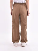 Pantalón marrón de corte ancho, con cintura elástica ajustable con cordón, bolsillos laterales y bolsillos tipo cargo en los muslos.
