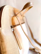 Mochila beige con detalles en blanco y marrón.