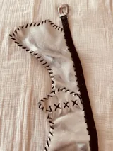 Cinturón de cuero negro con hebilla plateada y riñonera plateada con flecos.