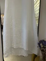 Vestido blanco de lino, corte acampanado, escote redondo, sin mangas y con bolsillos laterales.