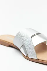 Sandalias bajas plateadas con tiras anchas cruzadas en el empeine y suela plana color marrón.