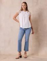 Blusa blanca de crepe marca Liv Los Ángeles, con hombros con aplique en crochet y espalda con abertura ojal y botones.