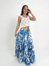 Falda larga de algodón con estampado floral en tonos marrón y blanco. Tiene elástico en la cintura y viene con un cinto de rafia elastizado desmontable.
