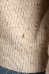 Cardigan de punto color beige melange con textura tweed, cuello alto y cierre frontal metálico. Corte ajustado al cuerpo y manga larga.