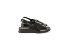 Sandalia de charol negro con tiras cruzadas, talón con elástico interno y plantilla de cuero acolchada.