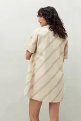 Vestido camisero corto color verde claro con estampado de hojas en blanco. Tiene cuello camisero, cierre frontal con botones y corte recto.