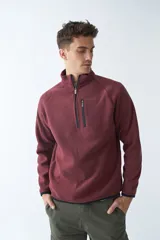Buzo polar de algodón color bordó, con cuello elevado, medio cierre frontal, bolsillo con cierre en el pecho y logo estampado.