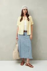 Falda midi de denim negro con tiro bajo, corte evasé, costuras verticales y ruedo desflecado.
