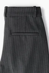 Pantalón de vestir gris oscuro con finas rayas verticales, corte ajustado, bolsillos laterales y traseros decorativos.