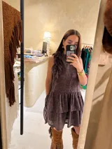 Vestido corto color cacao con encaje calado, cuello alto con volados, sin mangas y falda con volados escalonados.