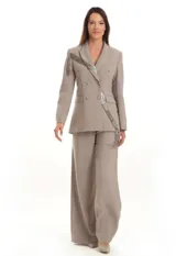 Blazer gris de corte estructurado con doble abotonadura y solapas clásicas. Presenta una aplicación de pedrería en cascada que recorre diagonalmente la prenda.