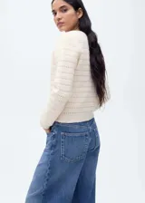 Chaqueta color crema de tejido de punto calado con mezcla de lana, cuello redondo y cierre frontal con botones.