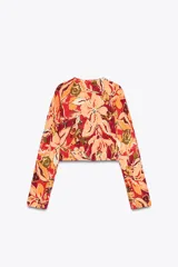 Top corto de punto con estampado floral en tonos rojo, naranja, verde y beige, cuello redondo y manga larga.