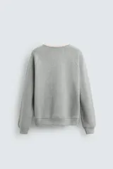 Sudadera gris de tejido compacto con mezcla de algodón y viscosa, corte relaxed fit, cuello redondo con rib combinado a contraste, manga larga y acabados en rib.