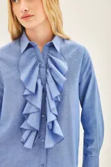 Camisa celeste de manga larga con volados en el frente y cuello clásico.