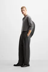 Pantalón relaxed fit color verde oscuro, con pliegues en la parte delantera, bolsillos laterales y traseros de ojal. Cierre frontal con cremallera y botón.