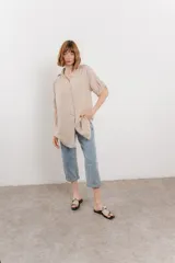 Camisa color beige de lino, con corte recto y calce suelto, cuello camisero, botones en el frente y mangas cortas con presilla y botón.