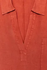 Vestido tipo túnica color ladrillo confeccionado en lino 100%. Tiene cuello solapa, escote pico, manga corta, bolsillos laterales ocultos y bolsillo de parche en el pecho. El bajo tiene aberturas laterales.