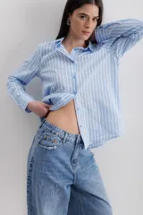 Camisa celeste a rayas verticales blancas, de corte clásico, con cuello camisero y mangas largas.