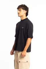 Remera negra de corte boxy con cuello subido y logo bordado en el pecho.