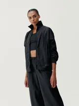 Chaqueta cortaviento verde oliva, de tejido técnico Wind_S, con cuello alto, cierre frontal y puños ajustables. Presenta un calce holgado y bolsillos con cremallera.