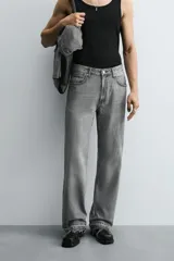 Pantalón de jean celeste de corte flare, con tiro medio, cinco bolsillos, cierre frontal con cremallera y botón, y bajo con acabado irregular.