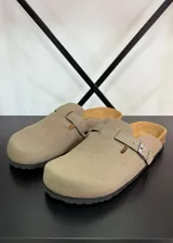 Zuecos color beige con hebilla lateral ajustable.