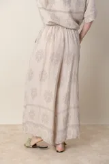 Pantalón palazzo de lino color crudo con estampado floral al tono, tiro alto y cintura elastizada.