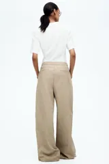 Pantalón color beige de corte ancho, con pinzas delanteras, cintura alta con elástico y bolsillos laterales.