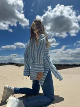 Camisa oversize celeste con rayas verticales blancas, de manga larga y cuello clásico.