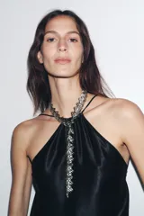 Collar metálico plateado con diseño de hojas y cierre de mosquetón.