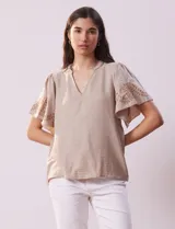 Blusa color beige de crepe, marca Batía, con cuello a la base y escote en V. Manga corta amplia con bordados.