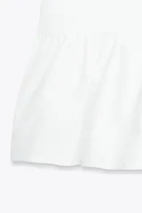 Top amarillo de escote pico y manga corta abullonada con elástico. Detalle de combinación de tejidos a tono y bajo con volante. Cierre frontal con lazadas.