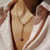 Collar dorado con cadena de eslabones rectangulares y dos dijes colgantes: uno de coral rojo y otro de aguamarina celeste.