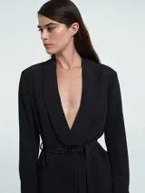 Chaqueta negra con hombreras, solapa delantera y lazo ajustable.