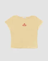 Remera color amarillo pastel, estilo baby tee, de algodón con cuello redondo y estampado pequeño de un postre con cereza.