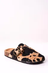 Zuecos con estampado de vaca en tonos camel y negro, con hebilla metálica ajustable y plantilla anatómica.